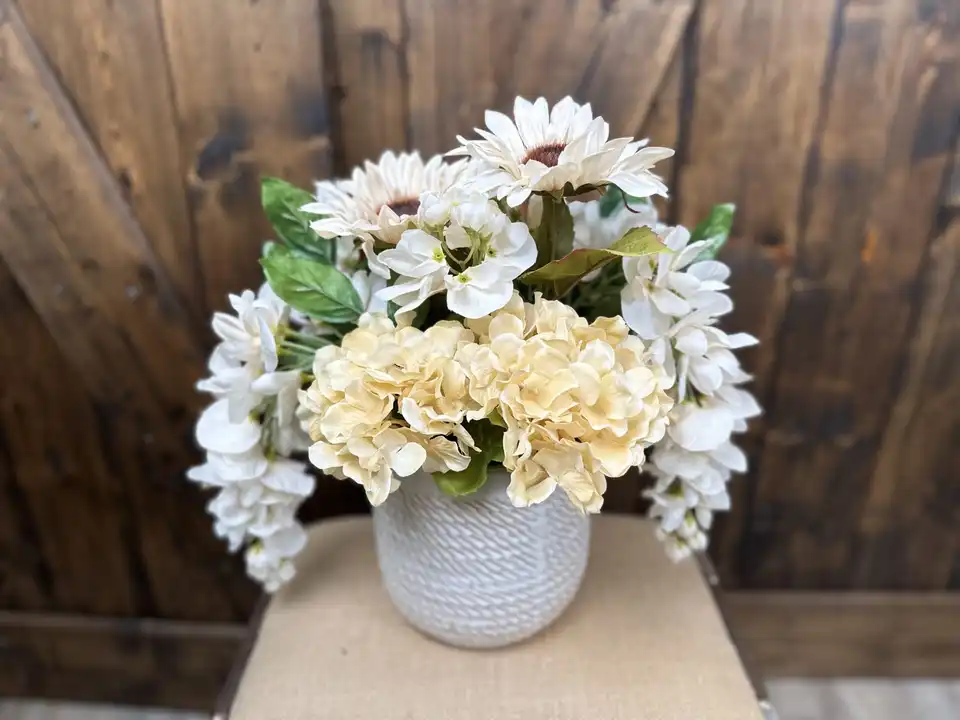 Cream hydrangea, white sunflowers and wisteria in a textured white vase