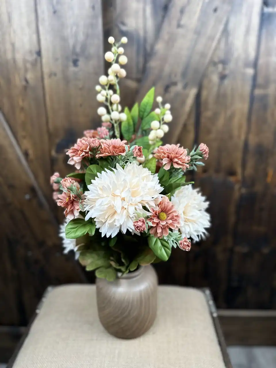 White dahlias, blush ranunculus and berry sprays in a ceramic vase