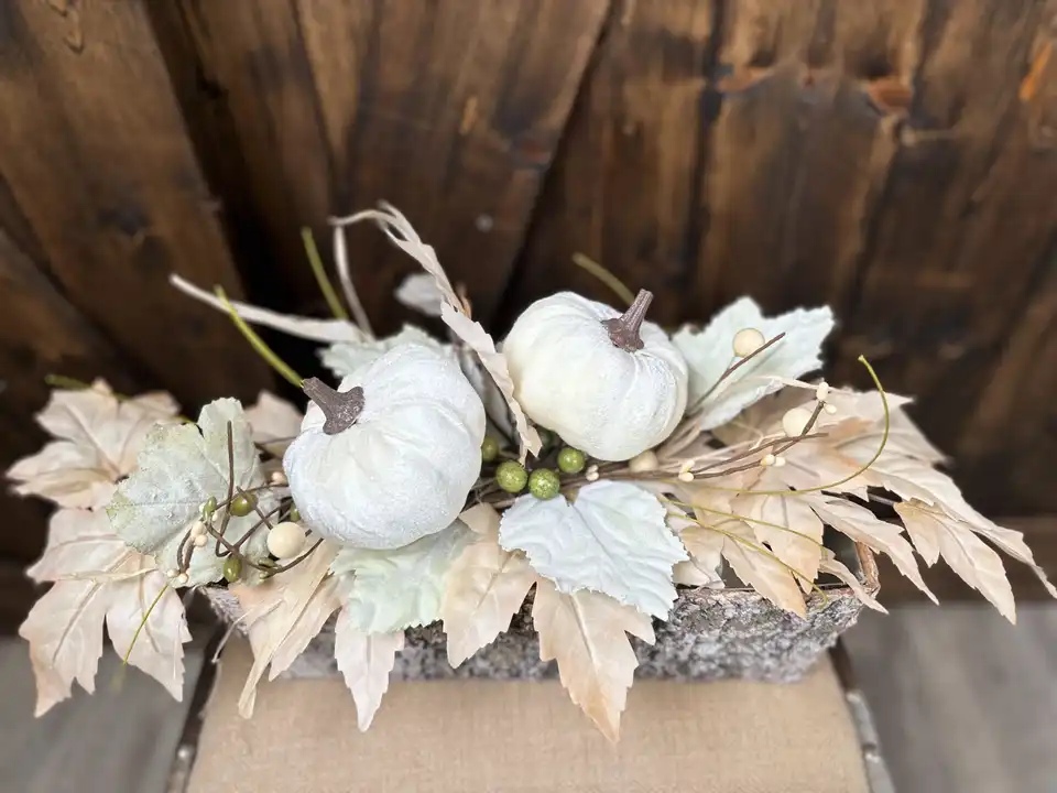 White pumpkin and dried leaf table runner in a rustic bark planter