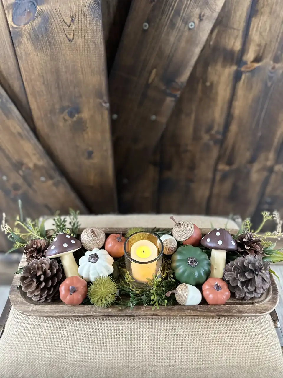 Woodland centerpiece with faux mushrooms, mini pumpkins, pinecones and a candle